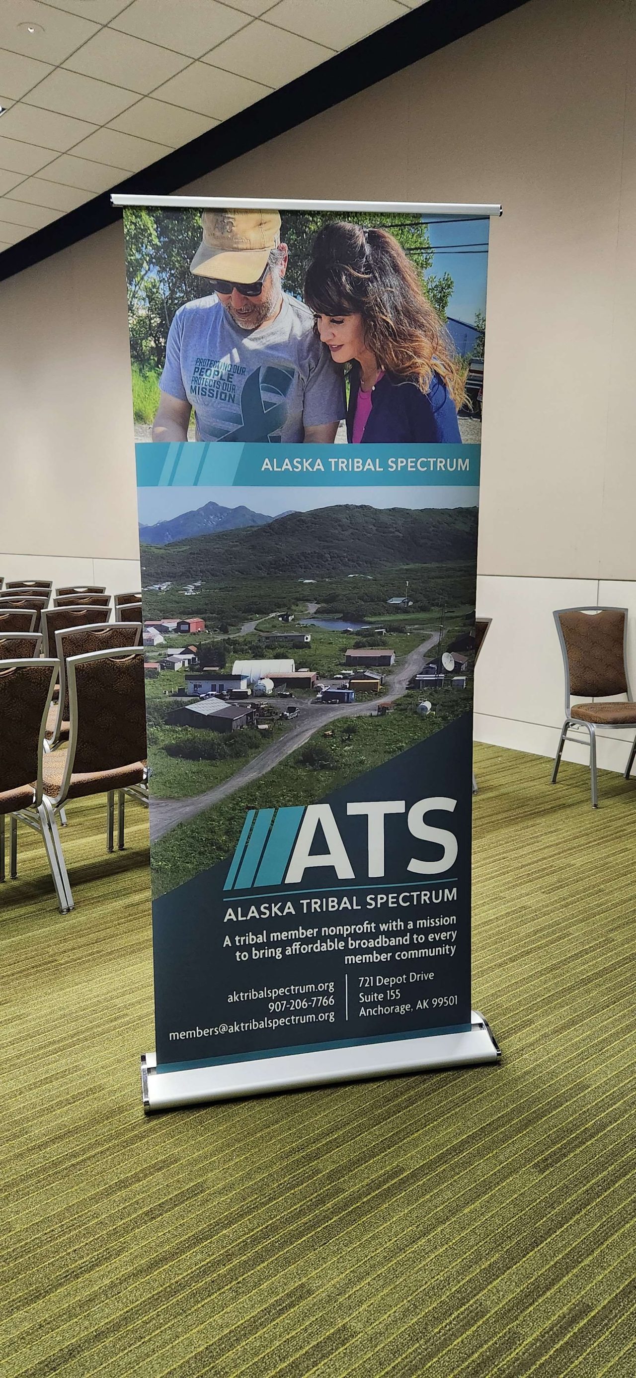 A tall free-standing banner with the ATS logo and basic information printed over photos.